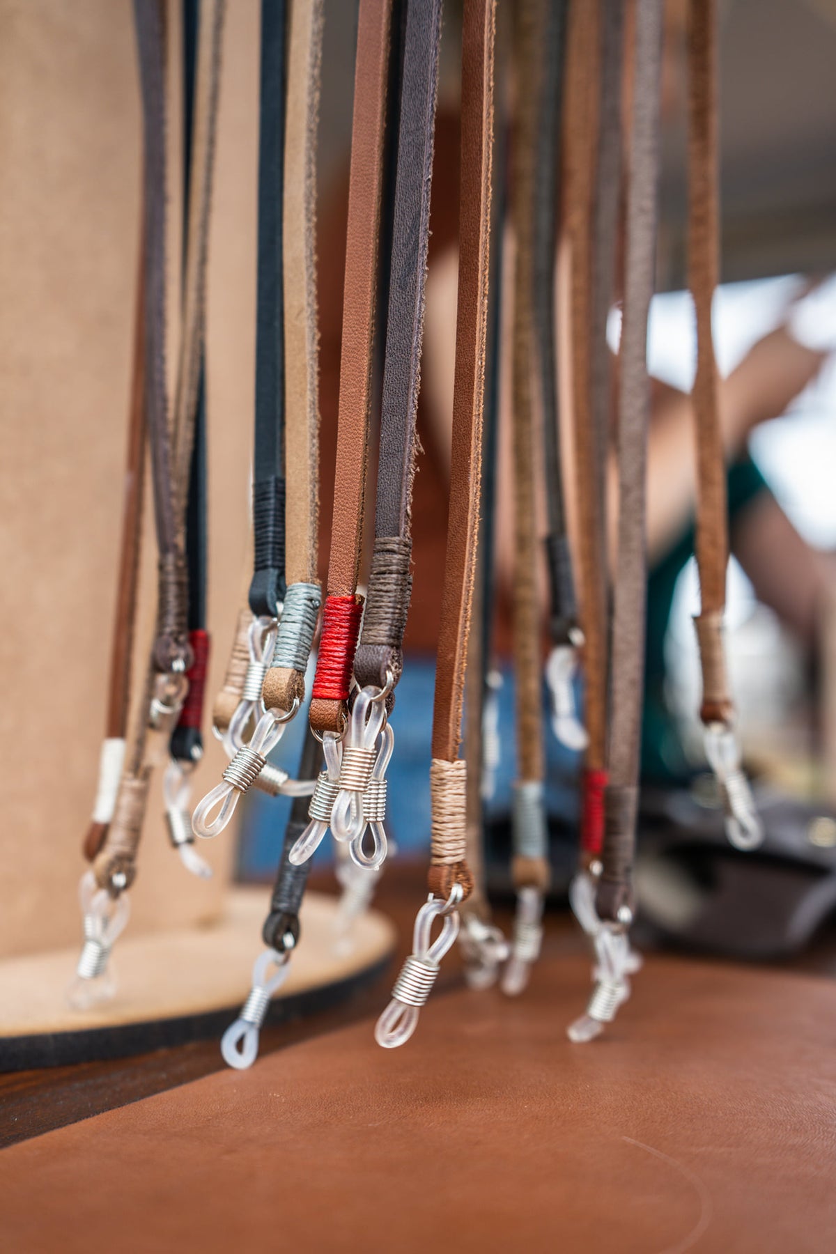 Collection of leather toutjies with various colors and designs hanging on a stand.