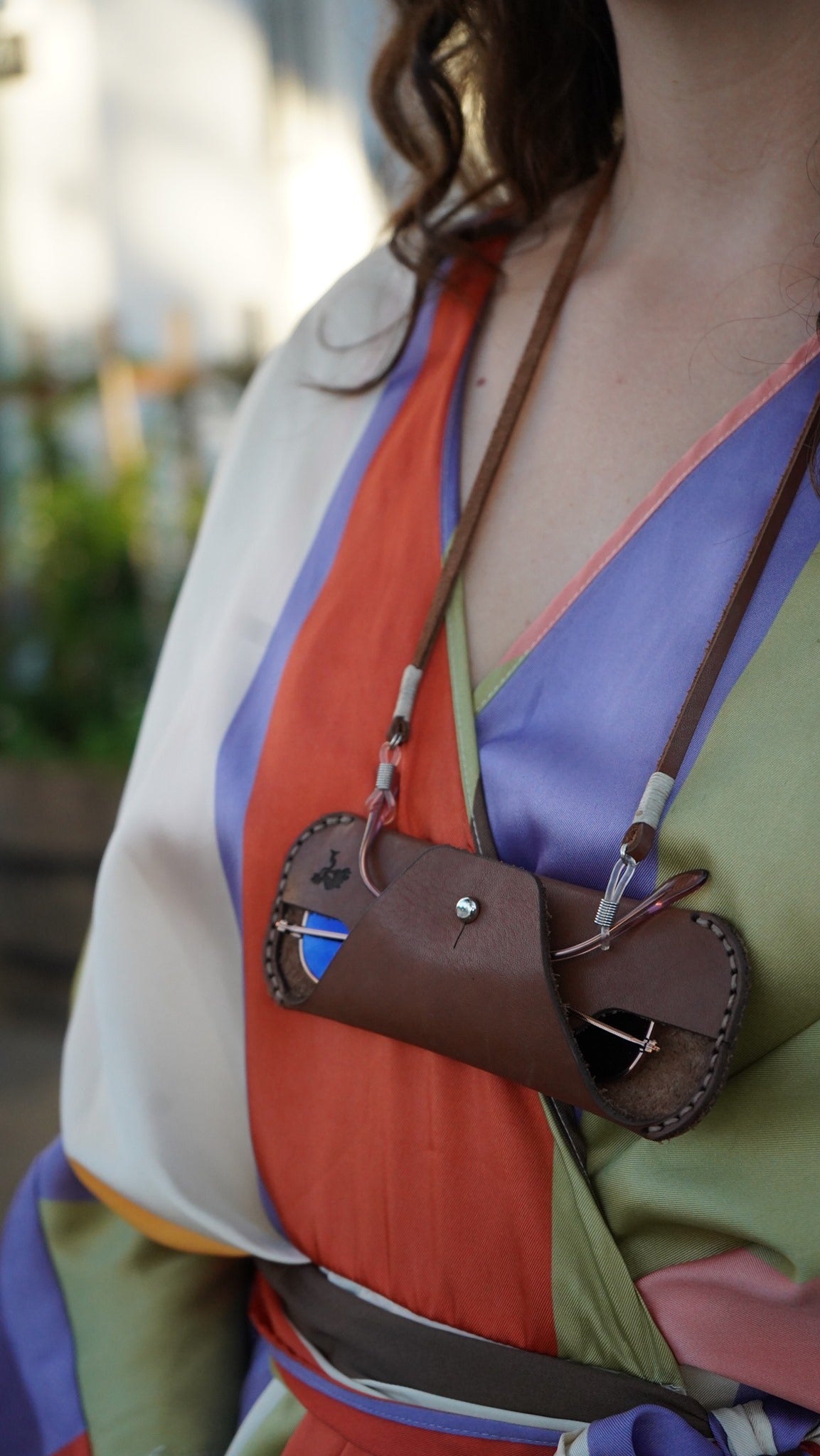 Person wearing a colorful outfit with a brown leather bag over their shoulder.