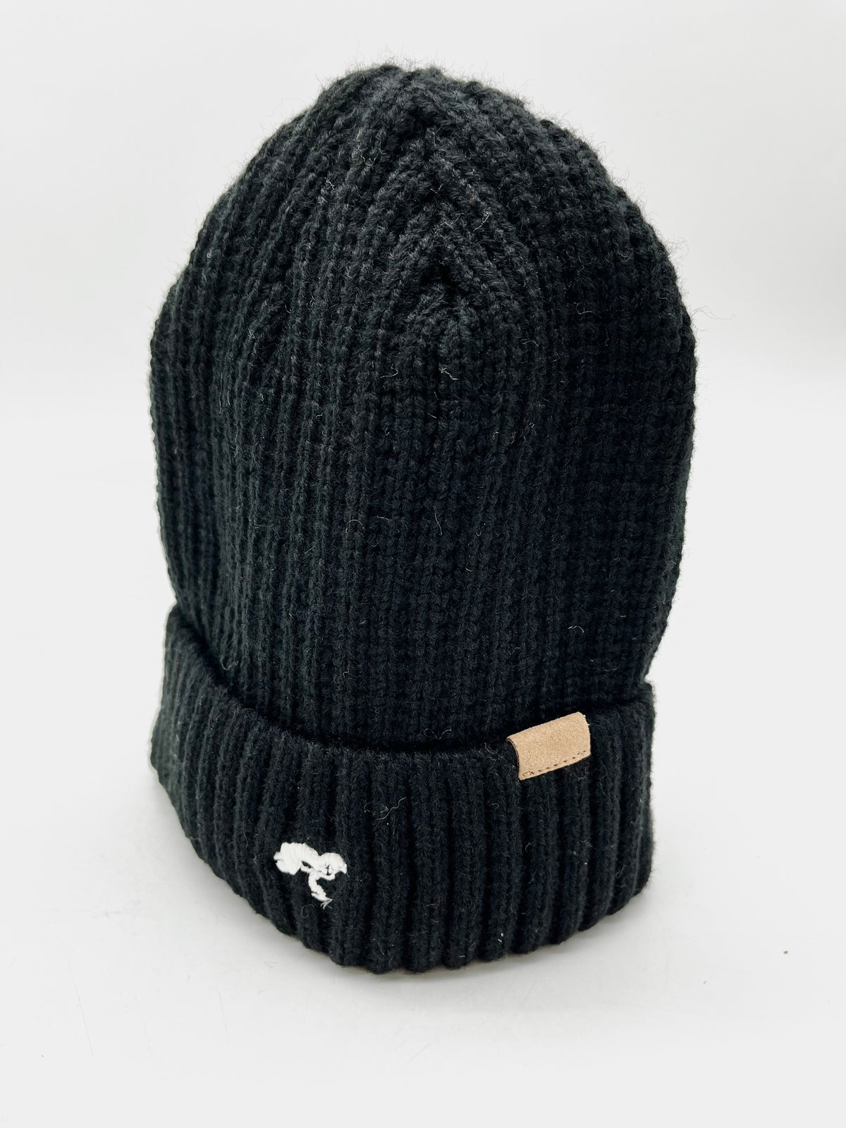 A black cotton beanie with a visible brand tag on it.