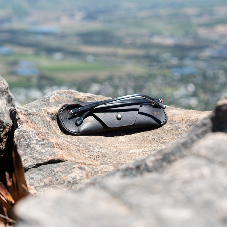 Black leather case with sunglasses on a rock with a scenic background