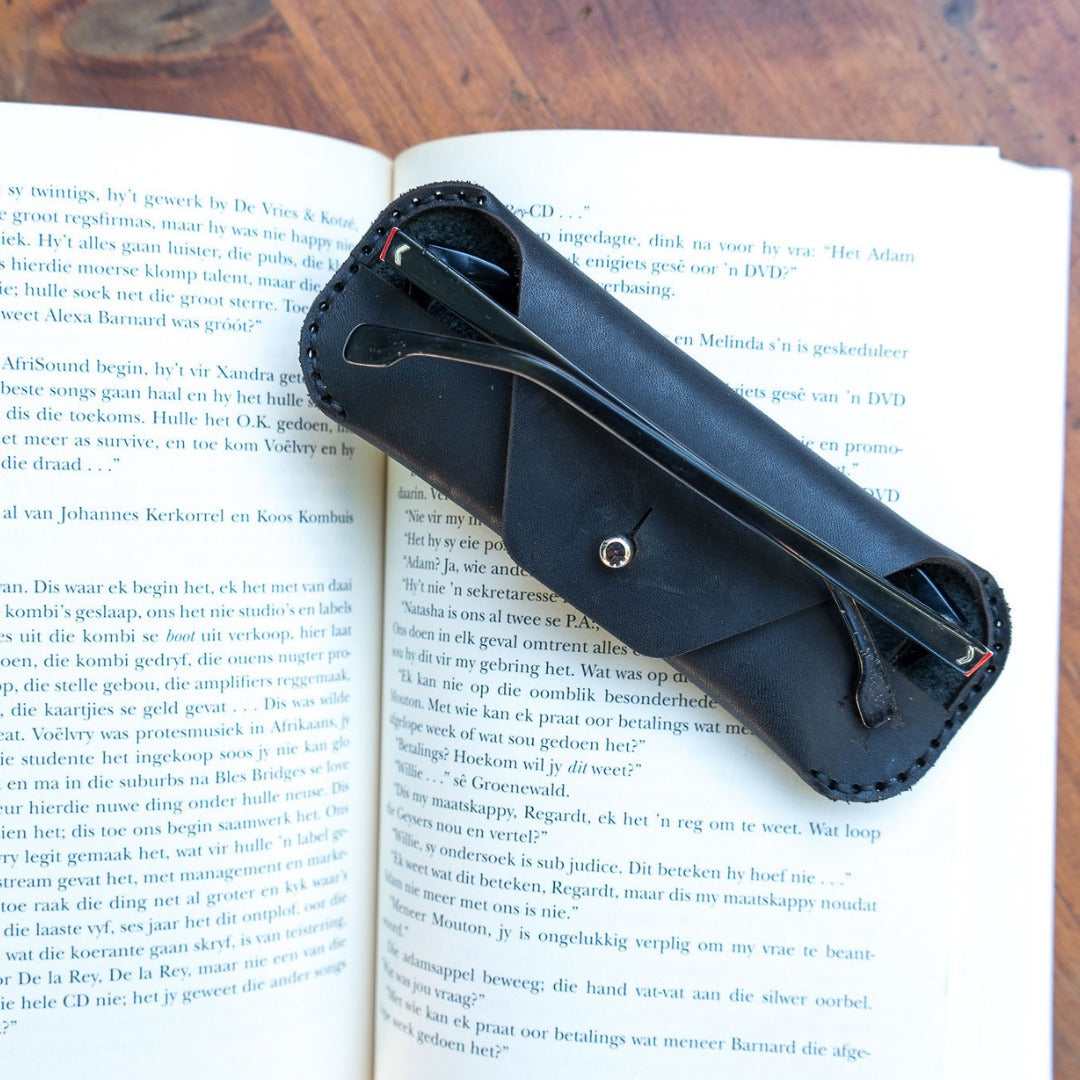 Black leather sunglasses case on a book