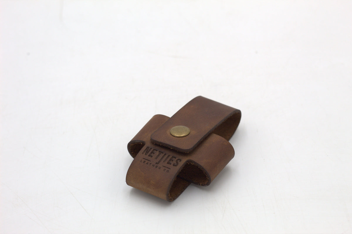 A brown leather cross wallet with a buckle closure.