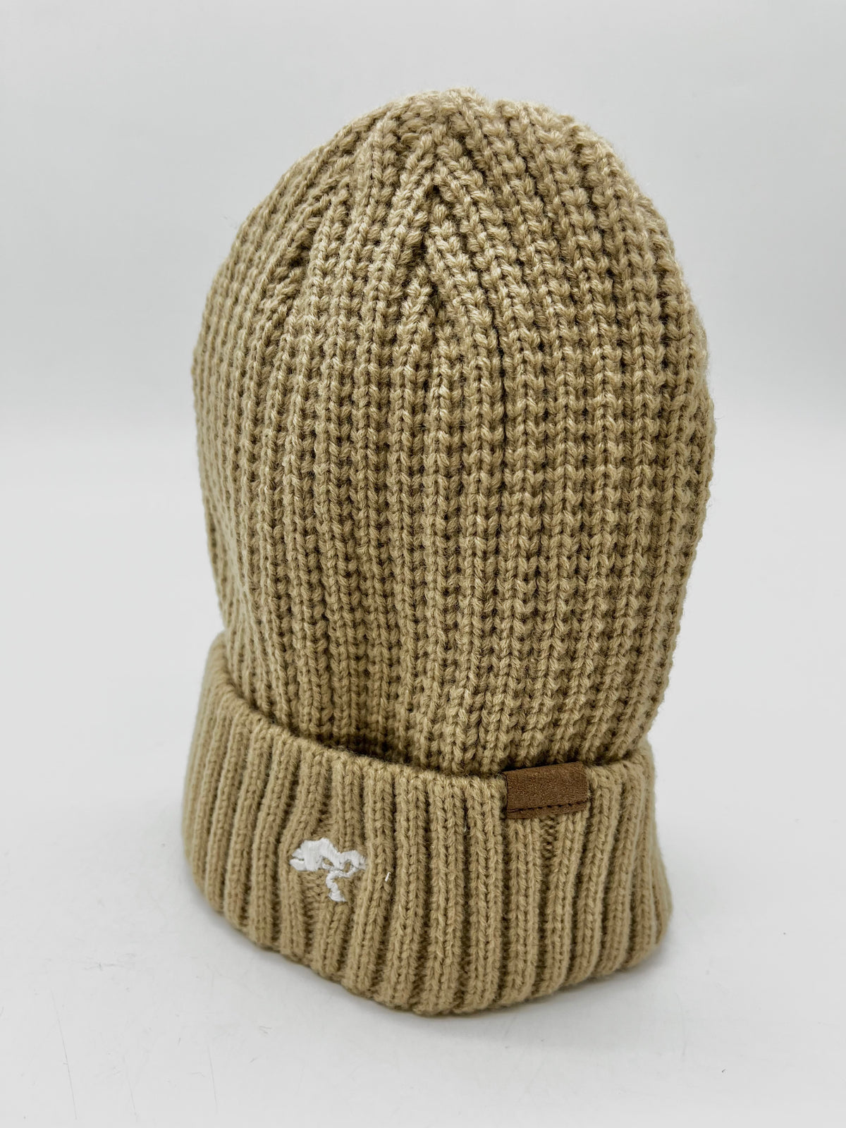 A beige cotton beanie with a visible brand tag on it.