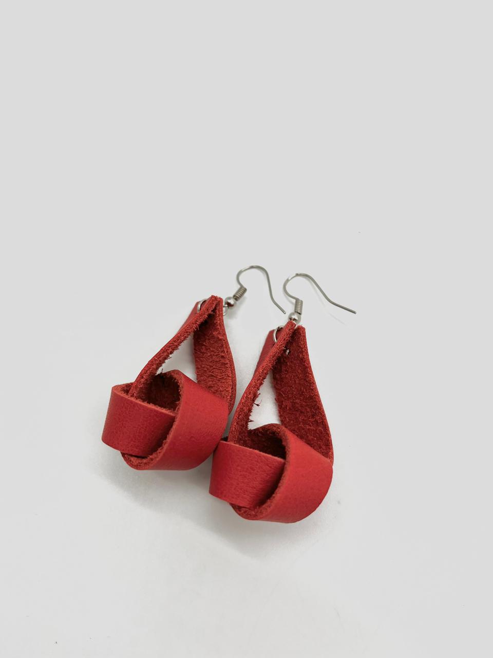 A pair of red leather earrings with a simple loop design, suspended from silver hooks.