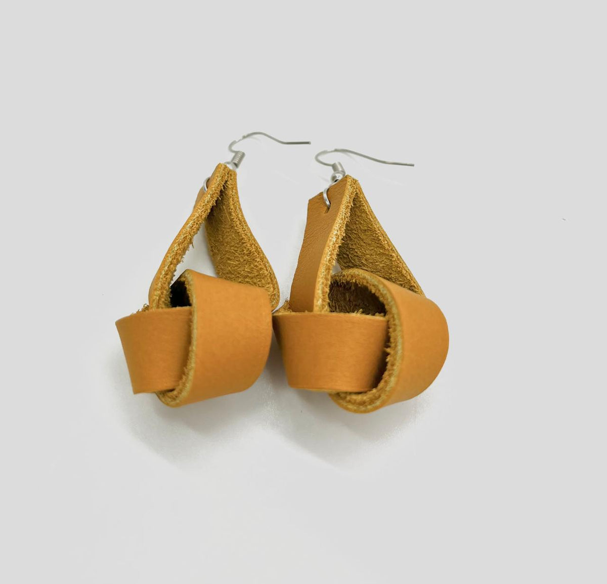 A pair of brown leather earrings with a simple loop design, suspended from silver hooks.