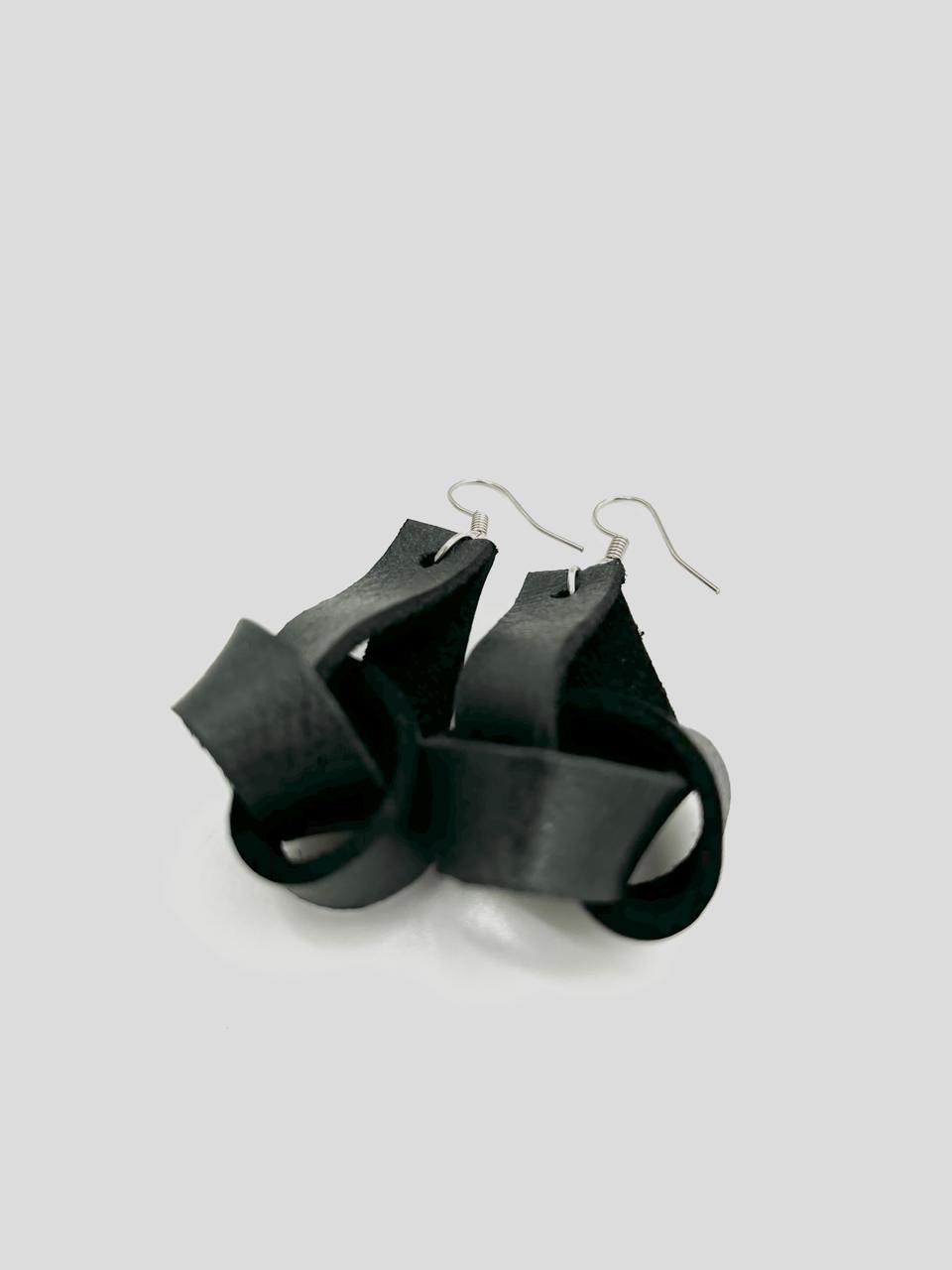 A pair of black leather earrings with a simple loop design, suspended from silver hooks.