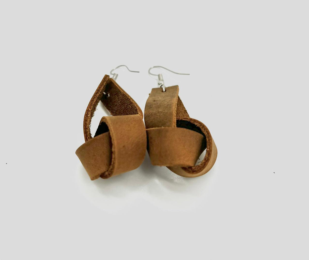 A pair of brown leather earrings with a simple loop design, suspended from silver hooks.