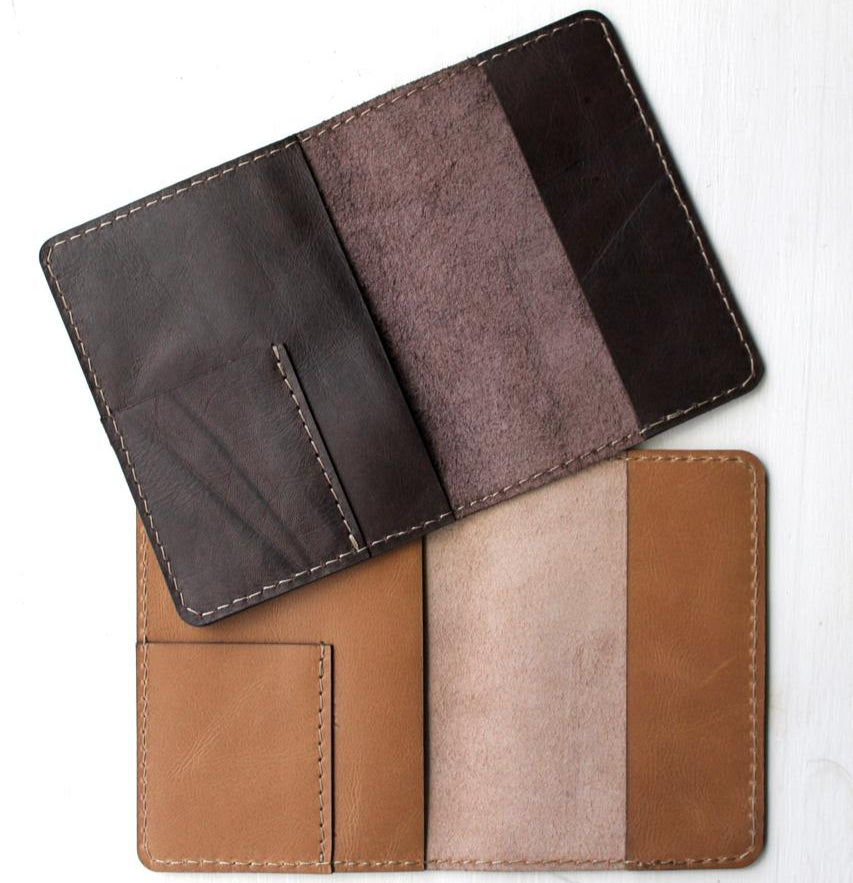 A set of two leather passport holders, one in brown and one in black, displayed open to show the interior compartments.