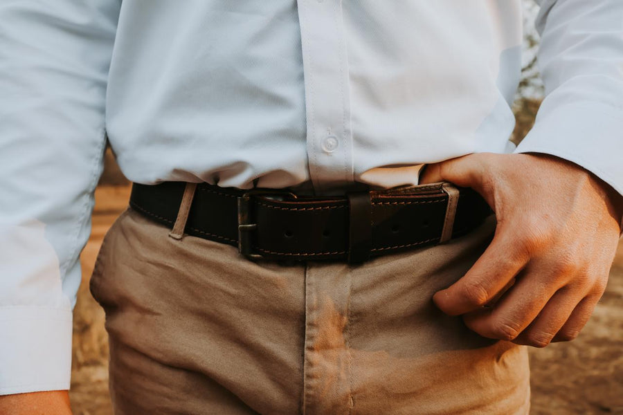 Person wearing a white shirt, brown belt, and beige pants with a blurred background