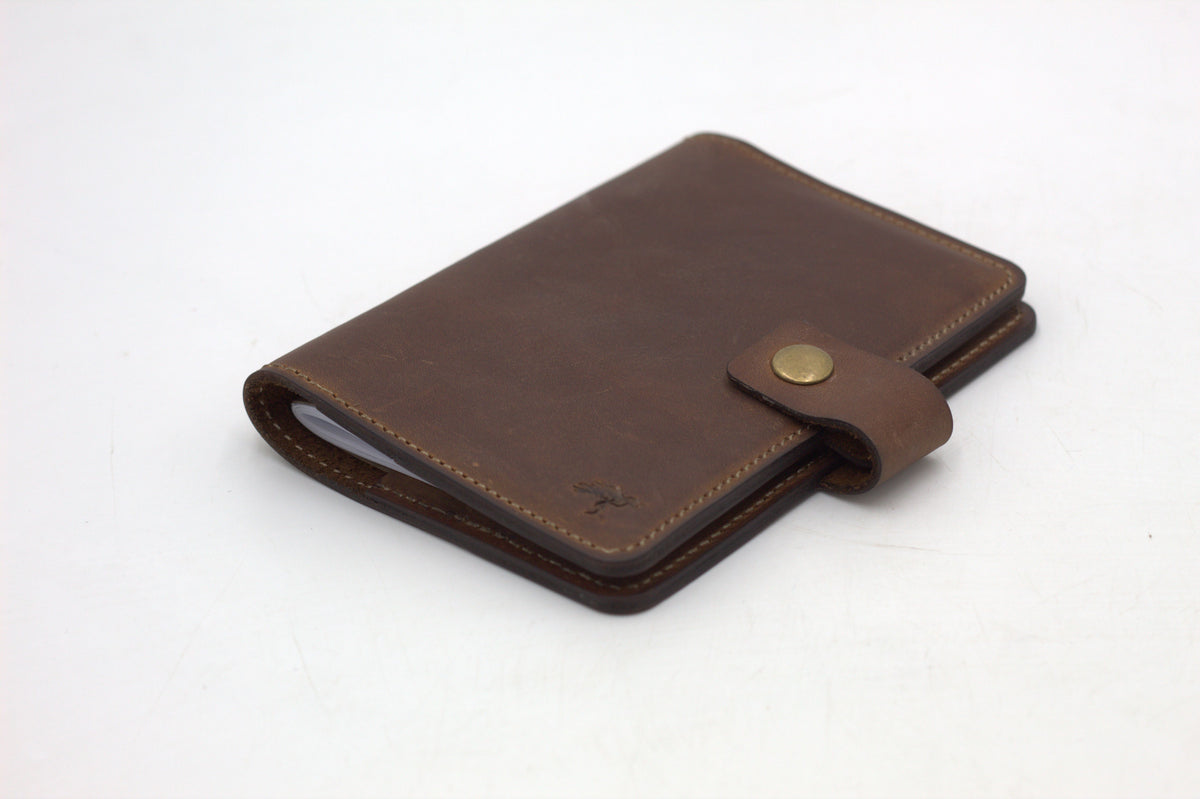 A black travel-wallet with a snap closure, displayed on a white background.