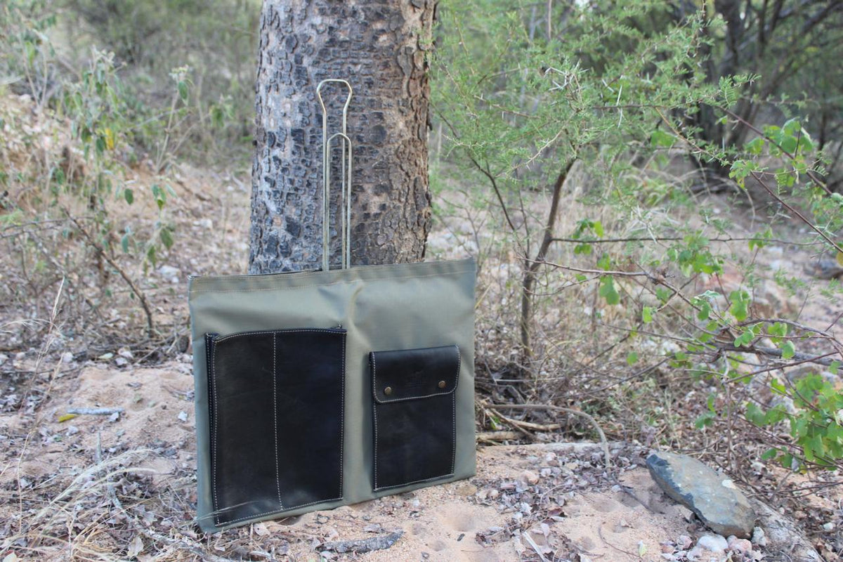 A green canvas bag hanging from a tree in a natural outdoor setting.