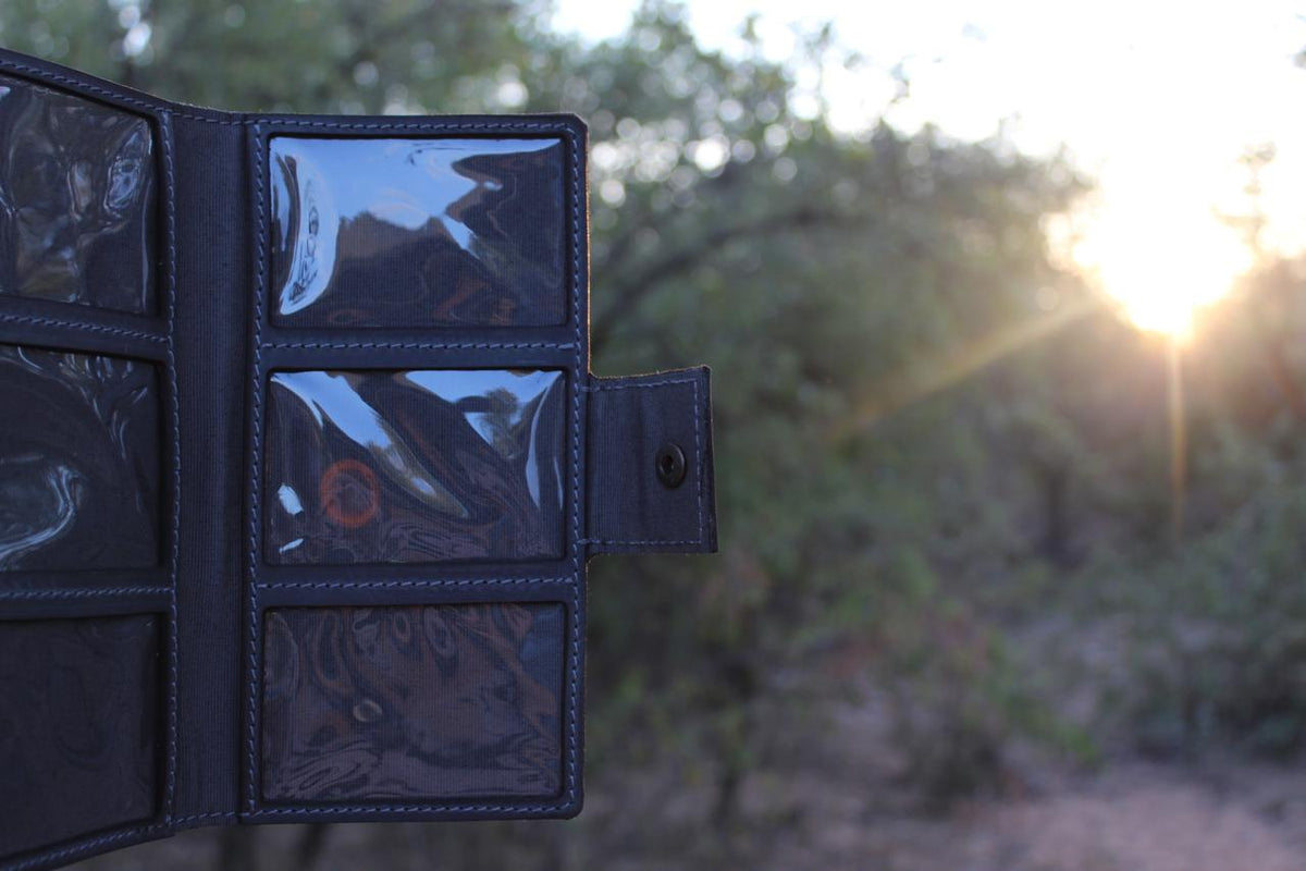 A black leather license holder opened to reveal six clear slots for firearm licenses