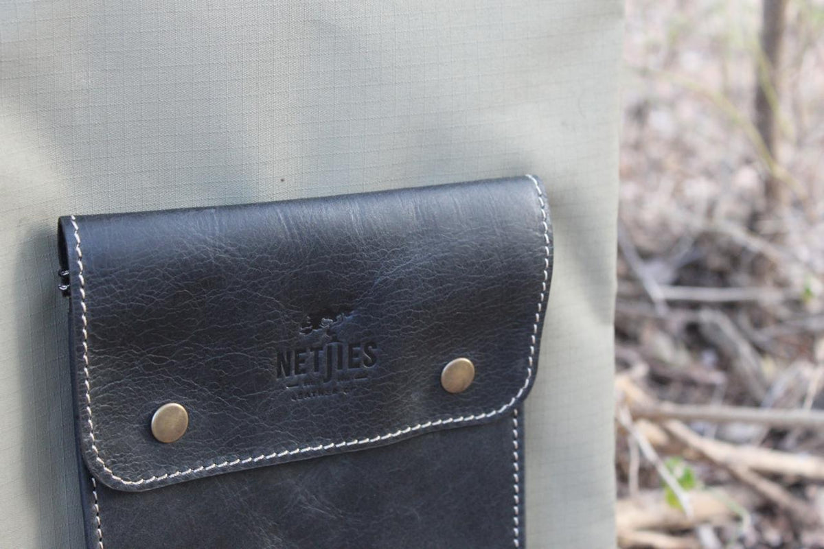 Netjies logo on a black leather pouch attached to a green canvas braai bag