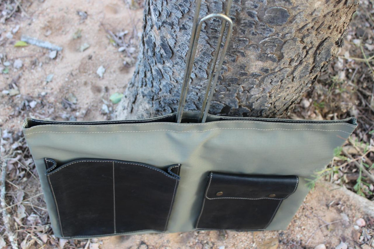 A green canvas bag hanging from a tree in a natural outdoor setting.