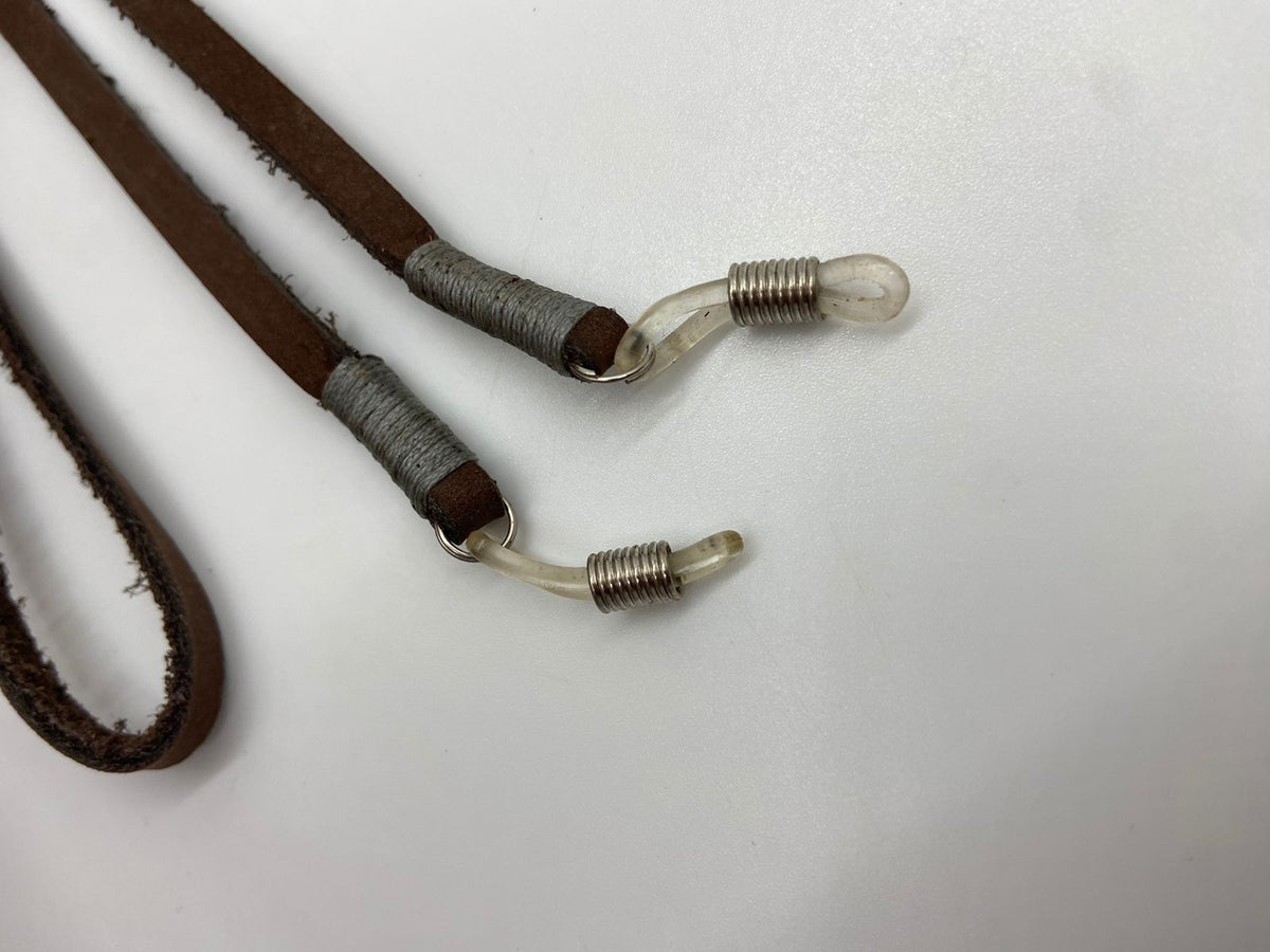 Two leather toutjies with metal clips on a white background