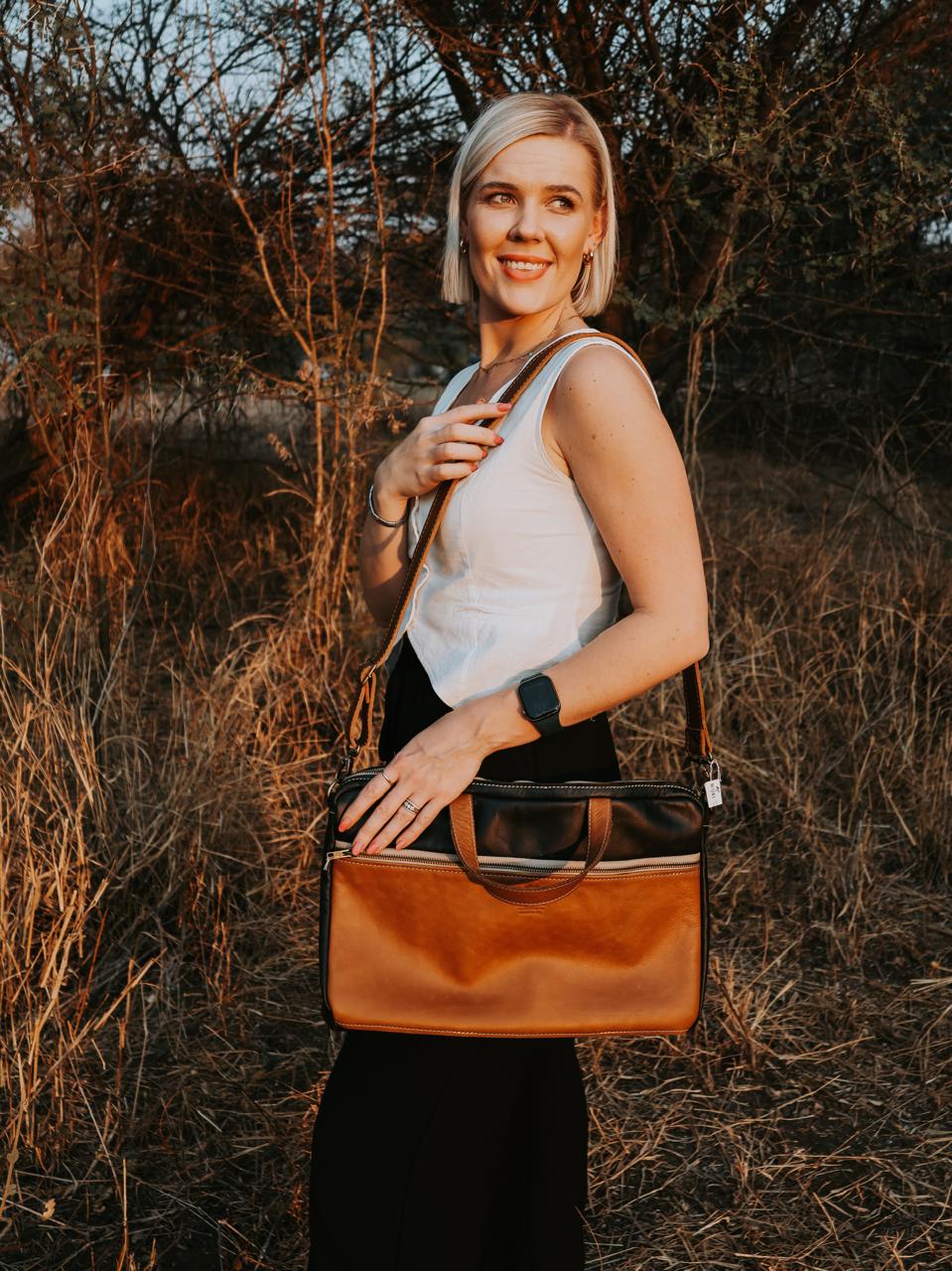 Woman holding a brown leather handbag in a natural setting