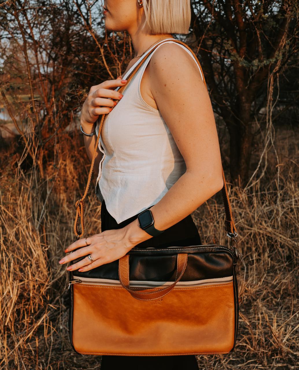 Woman holding a brown leather bag in a natural setting