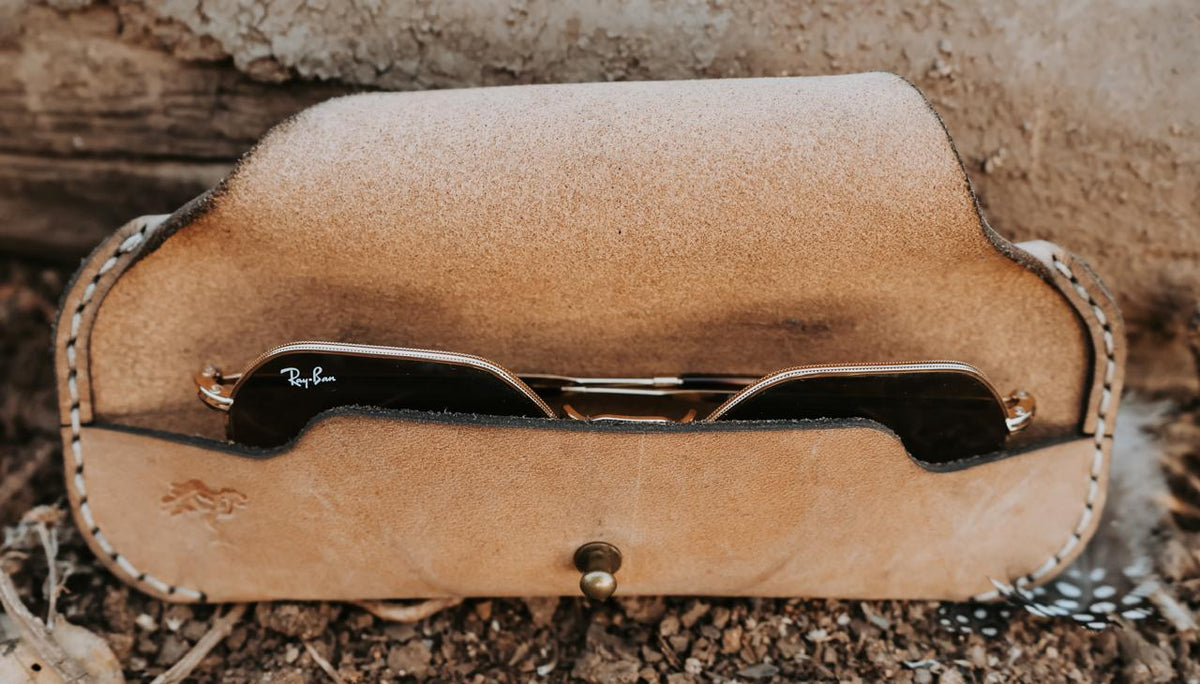 Close-up of a leather case with a brand logo on a natural background