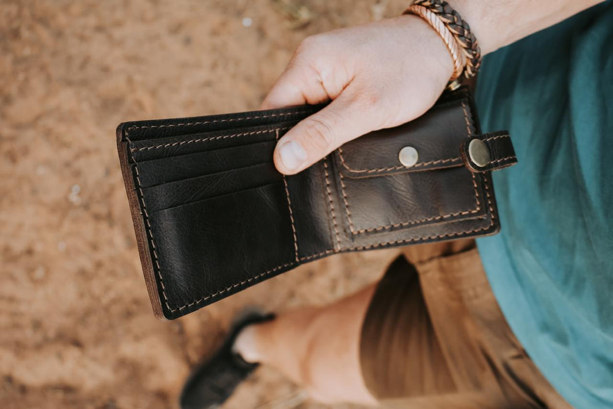 Person holding a brown leather wallet with a blurred background