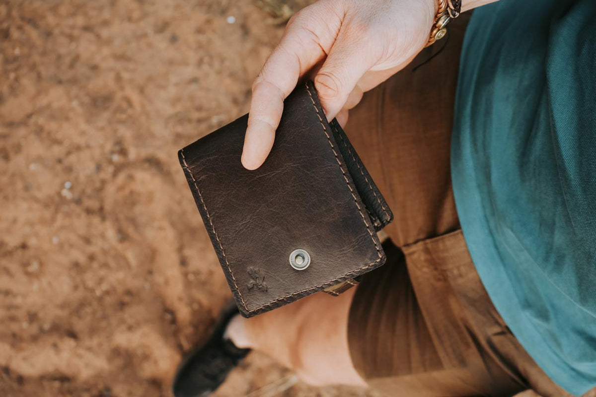 Person holding a brown leather wallet with a blurred background