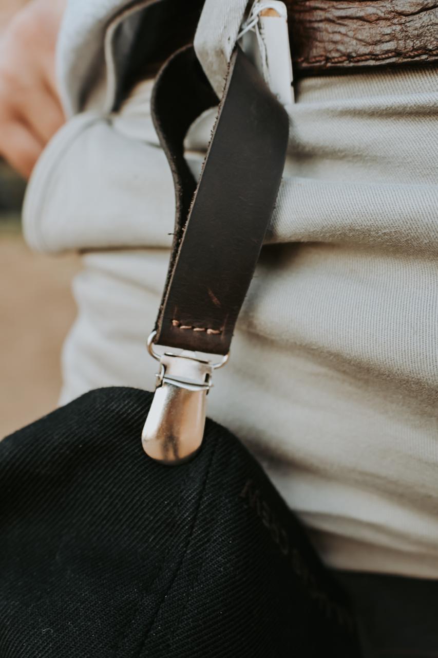 Close-up of a black hat clip with a metal clip on a beige background