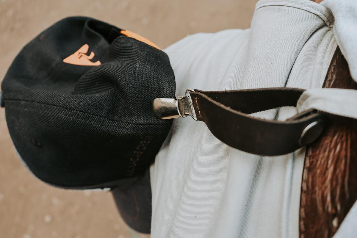Black cap with a strap over a white hoodie on a blurred background