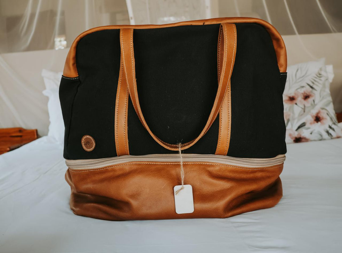 Black and brown bag with a tag on a bed