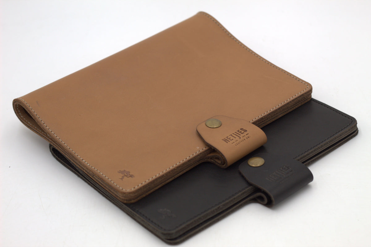 A brown leather journal cover with a black flap and a visible brand tag on the bottom right.