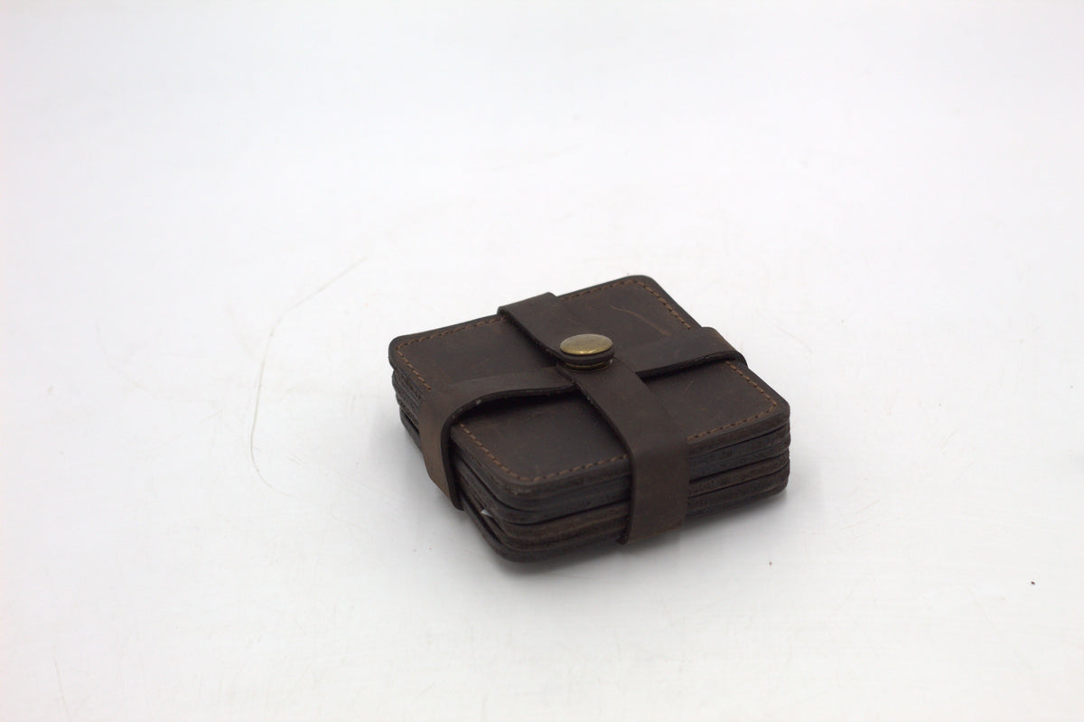A set of four brown leather coasters with a holder.