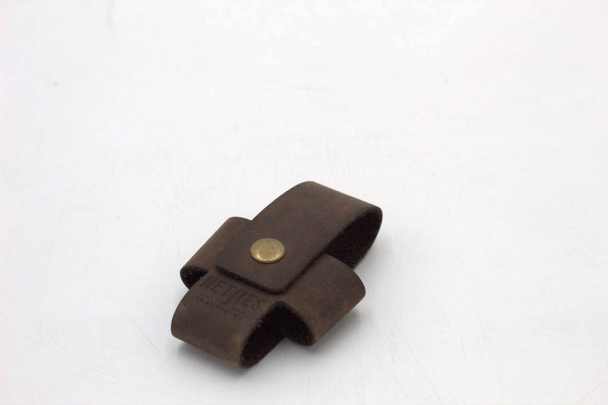 A brown leather cross wallet with a buckle closure.