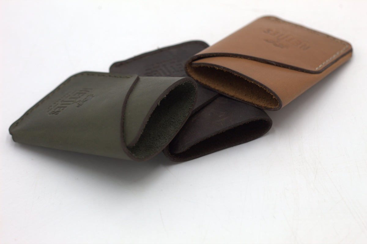 Three leather coin purses, one in brown, one in black, and one in green, arranged together.