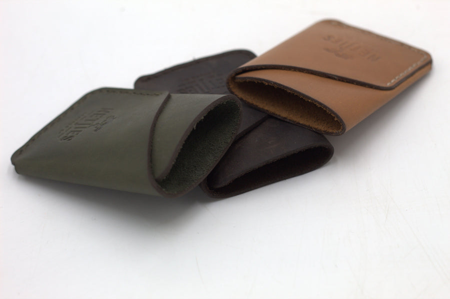 Three leather coin purses, one in brown, one in black, and one in green, arranged together.