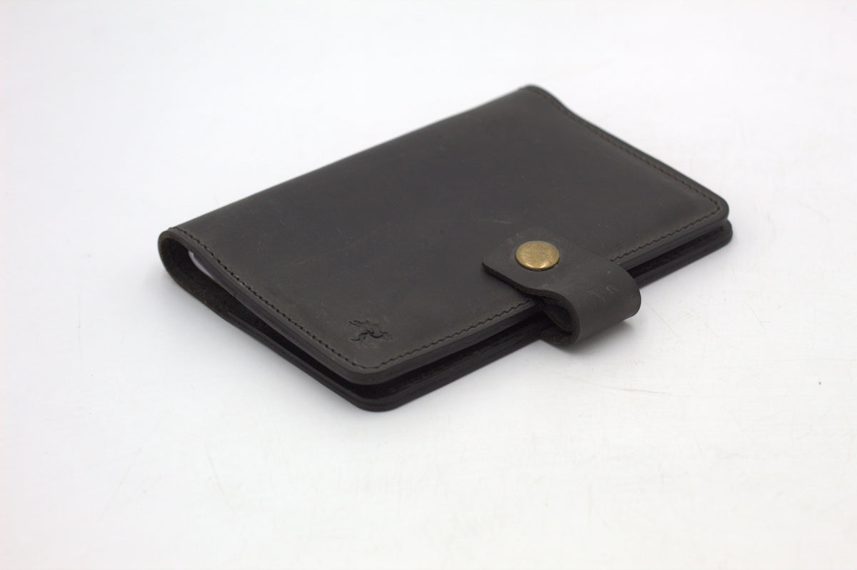 A black travel-wallet with a snap closure, displayed on a white background.