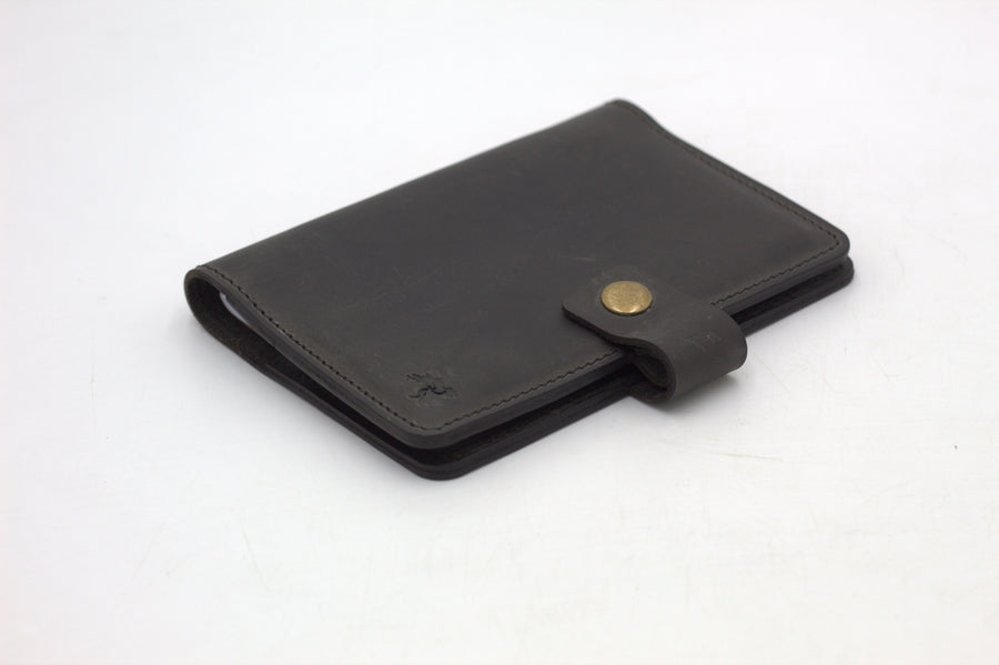 A black travel-wallet with a snap closure, displayed on a white background.