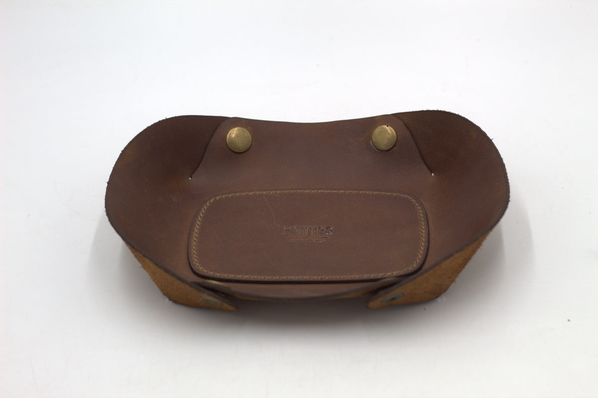 A brown leather vallet tray with two metal studs, photographed on a white background.