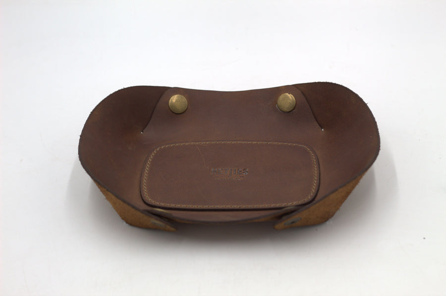 A brown leather vallet tray with two metal studs, photographed on a white background.